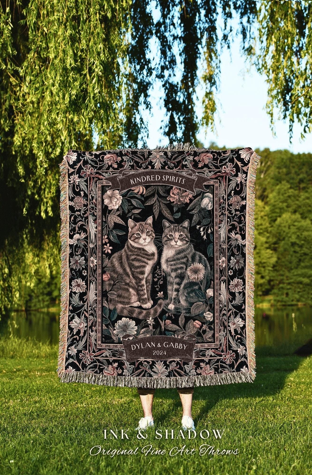May include: A black woven throw blanket with a floral pattern and two cats sitting in the center. The blanket has the text "Kindred Spirits" and "Dylan & Gabby 2024" on it. The text "Ink & Shadow Original Fine Art Throws" is at the bottom of the image.