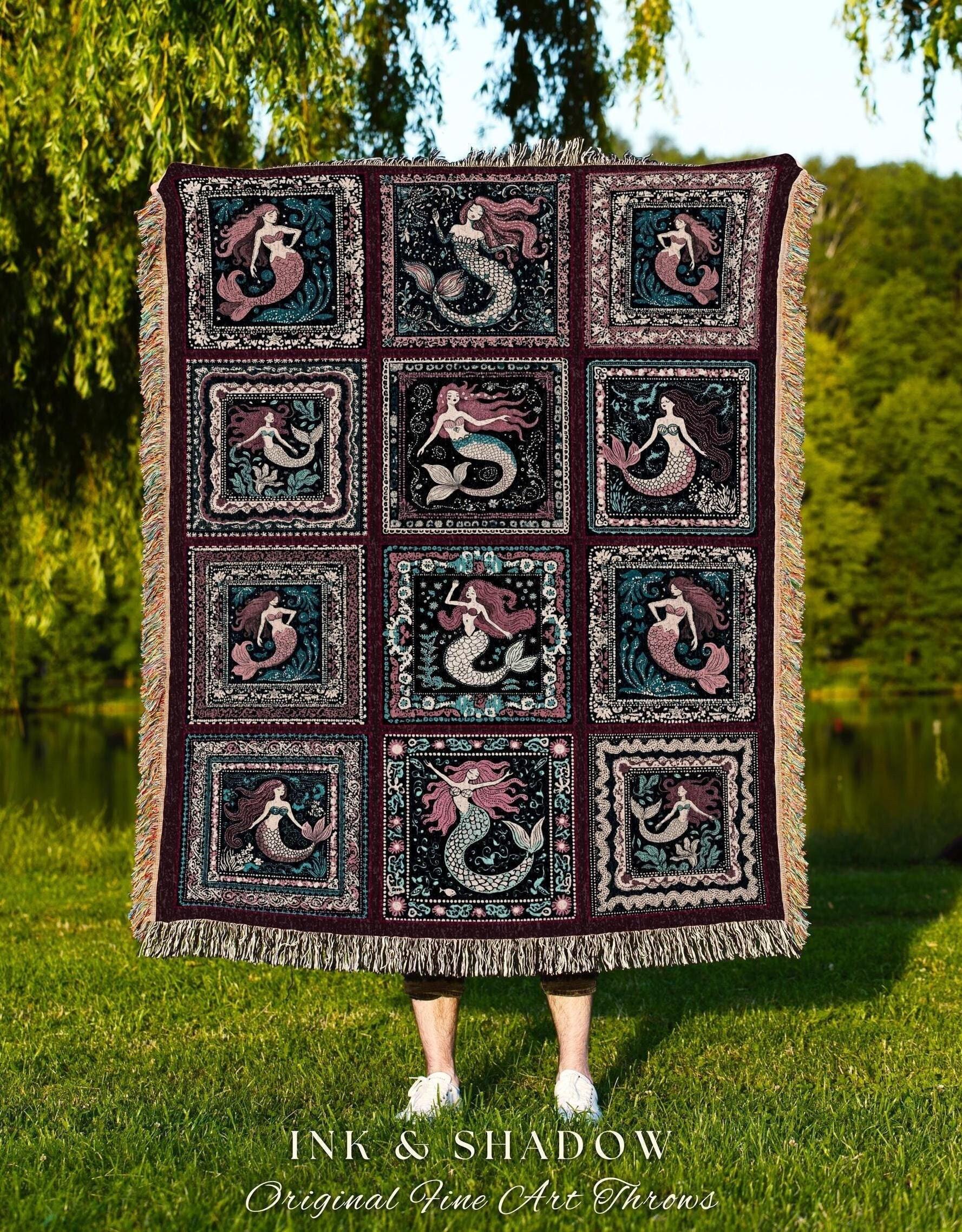 May include: A dark burgundy throw blanket featuring a repeating pattern of mermaids in square frames. The mermaids have flowing hair and fish tails in shades of pink, teal, and white. The blanket has a fringed edge and the text "INK & SHADOW Original Fine Art Throws".