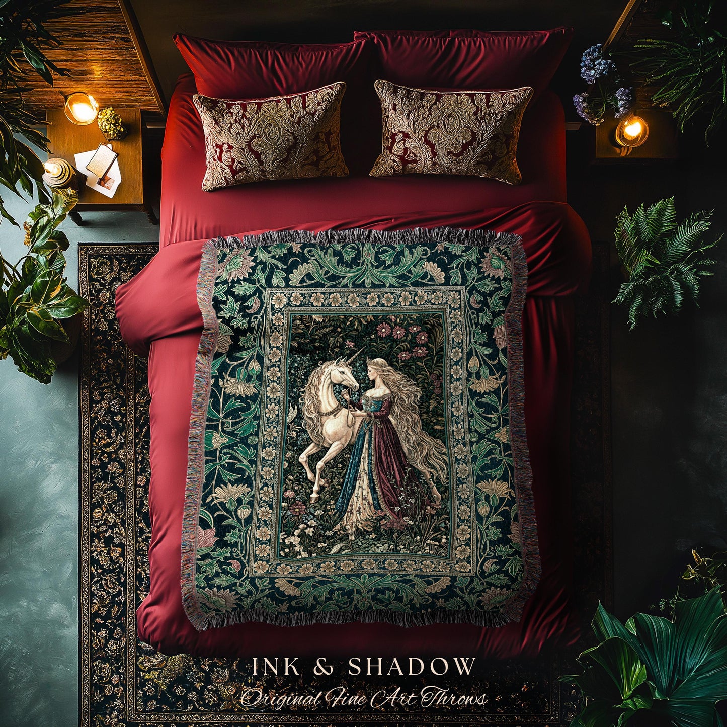 May include: A tapestry throw blanket featuring a woman and a unicorn, with a floral border. The throw is displayed on a red bed with matching pillows. The text "INK & SHADOW Original Fine Art Throws" is at the bottom.