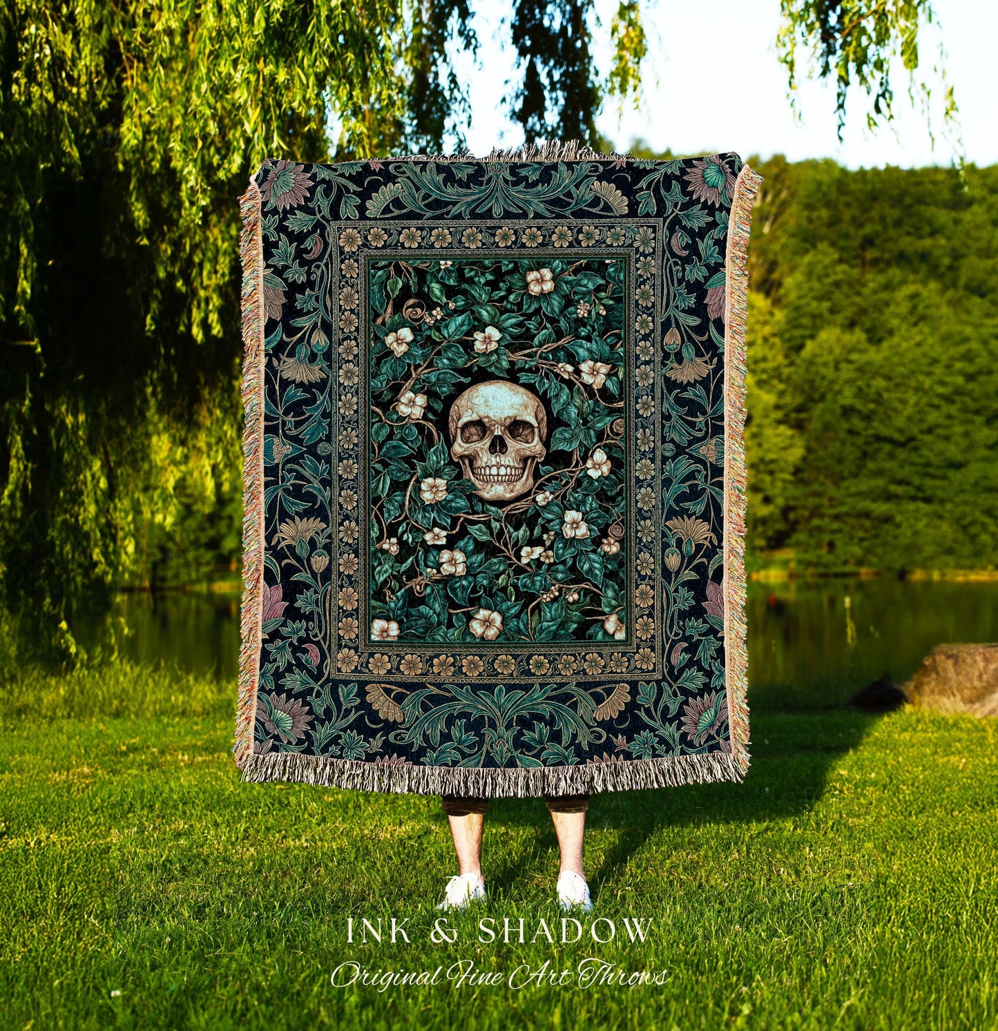 May include: A dark green throw blanket with a floral and skull design. The center features a skull surrounded by white flowers and green leaves. The blanket has a fringed edge and the text "INK & SHADOW Original Fine Art Throws" at the bottom.