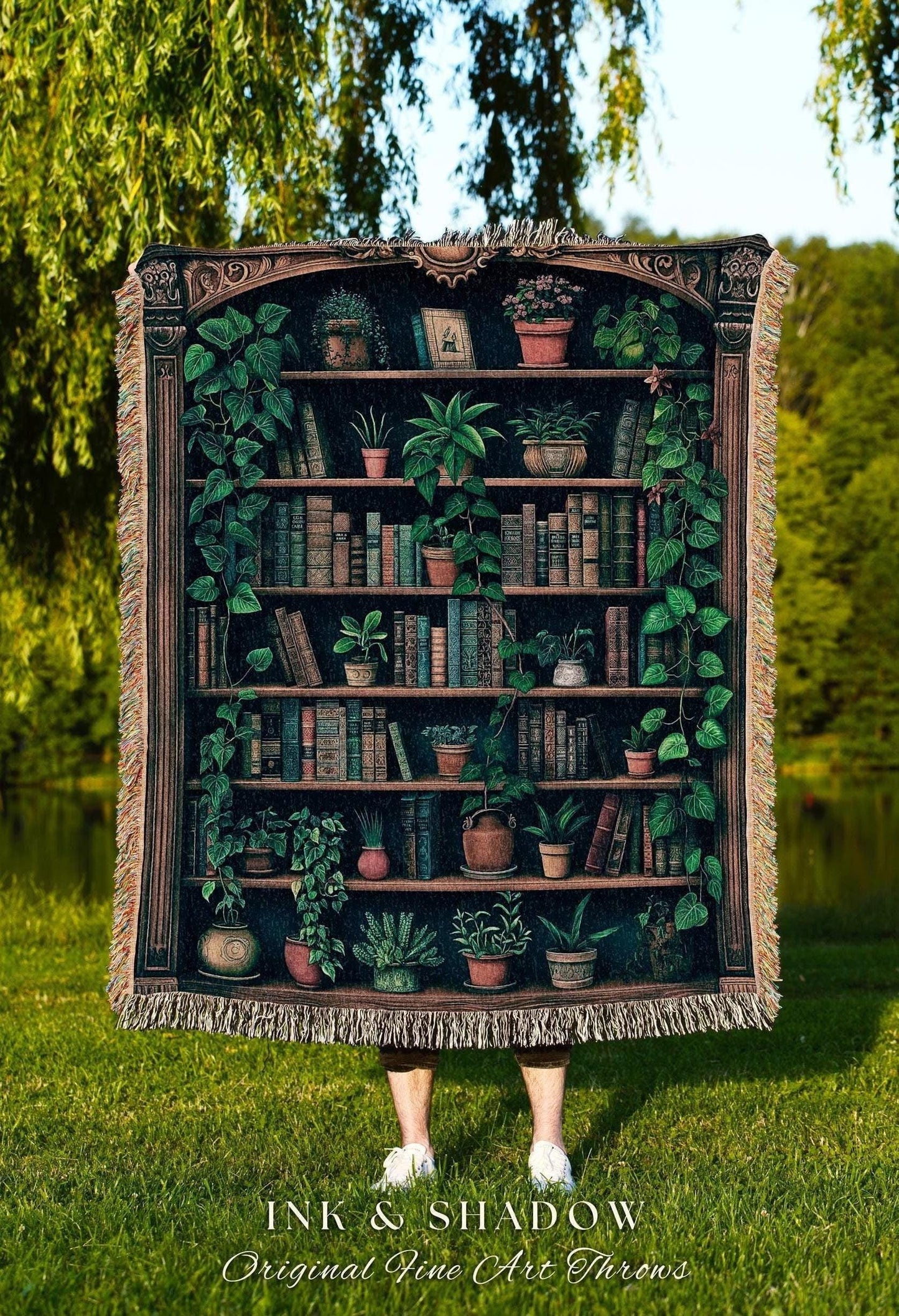 May include: A tapestry throw blanket featuring a detailed illustration of a bookshelf filled with books and potted plants. The design includes a dark brown frame and is fringed on the edges. The text "INK & SHADOW Original Fine Art Throws" is at the bottom.