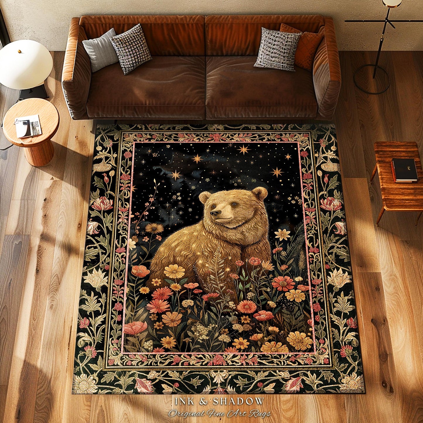 May include: A dark-colored rug features a whimsical design of a brown bear sitting amidst a garden of colorful flowers under a night sky with stars. The rug has a vintage, tapestry-like border. The text 'INK & SHADOW Original Fine Art Rugs' is visible at the bottom. The rug is displayed on a hardwood floor in a living room setting.