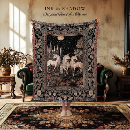 May include: A black tapestry throw blanket with a detailed illustration of three unicorns under a starry night sky. The blanket has a fringed edge and floral border. Text at the top reads "INK & SHADOW Original Fine Art Throws."