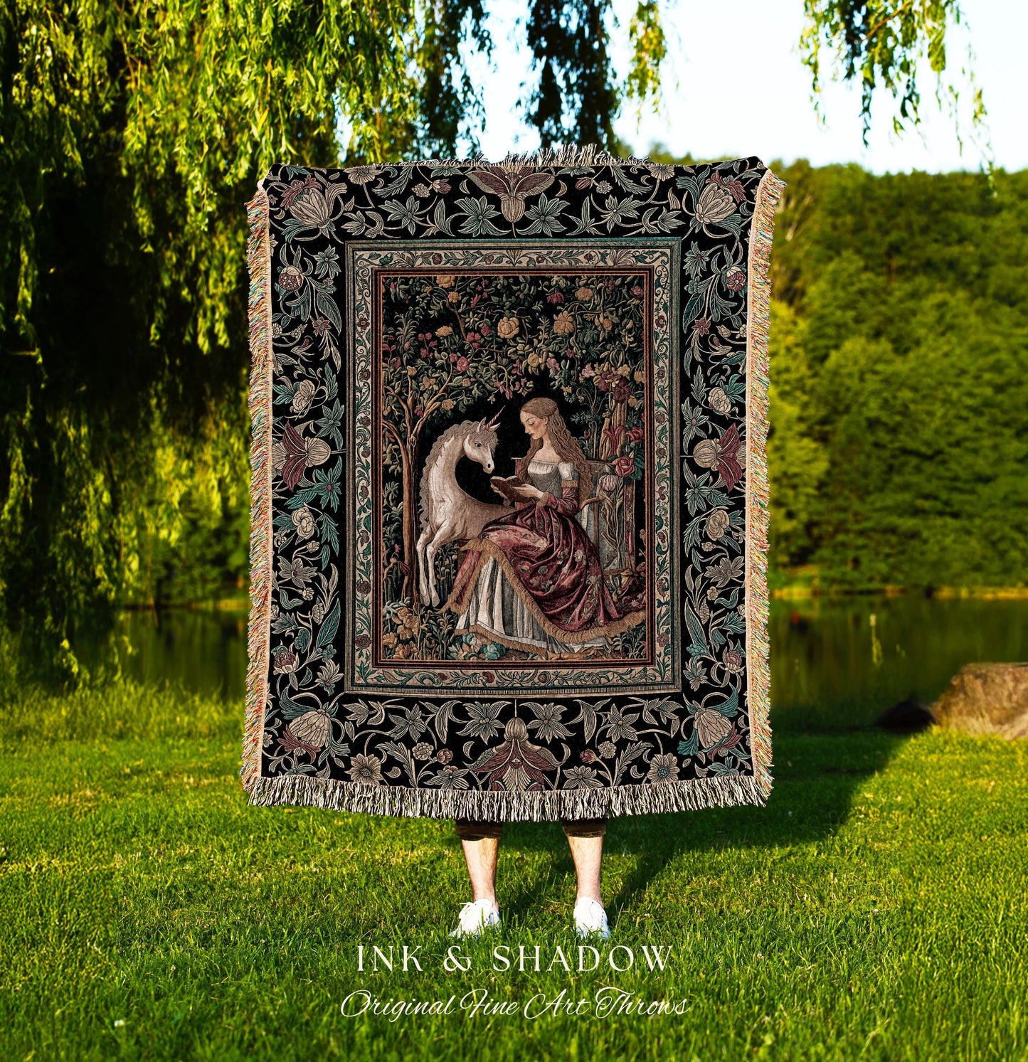 May include: A tapestry throw blanket featuring a medieval scene with a unicorn and a woman reading. The throw has a black background with floral and foliage patterns. The text "INK & SHADOW Original Fine Art Throws" is at the bottom.