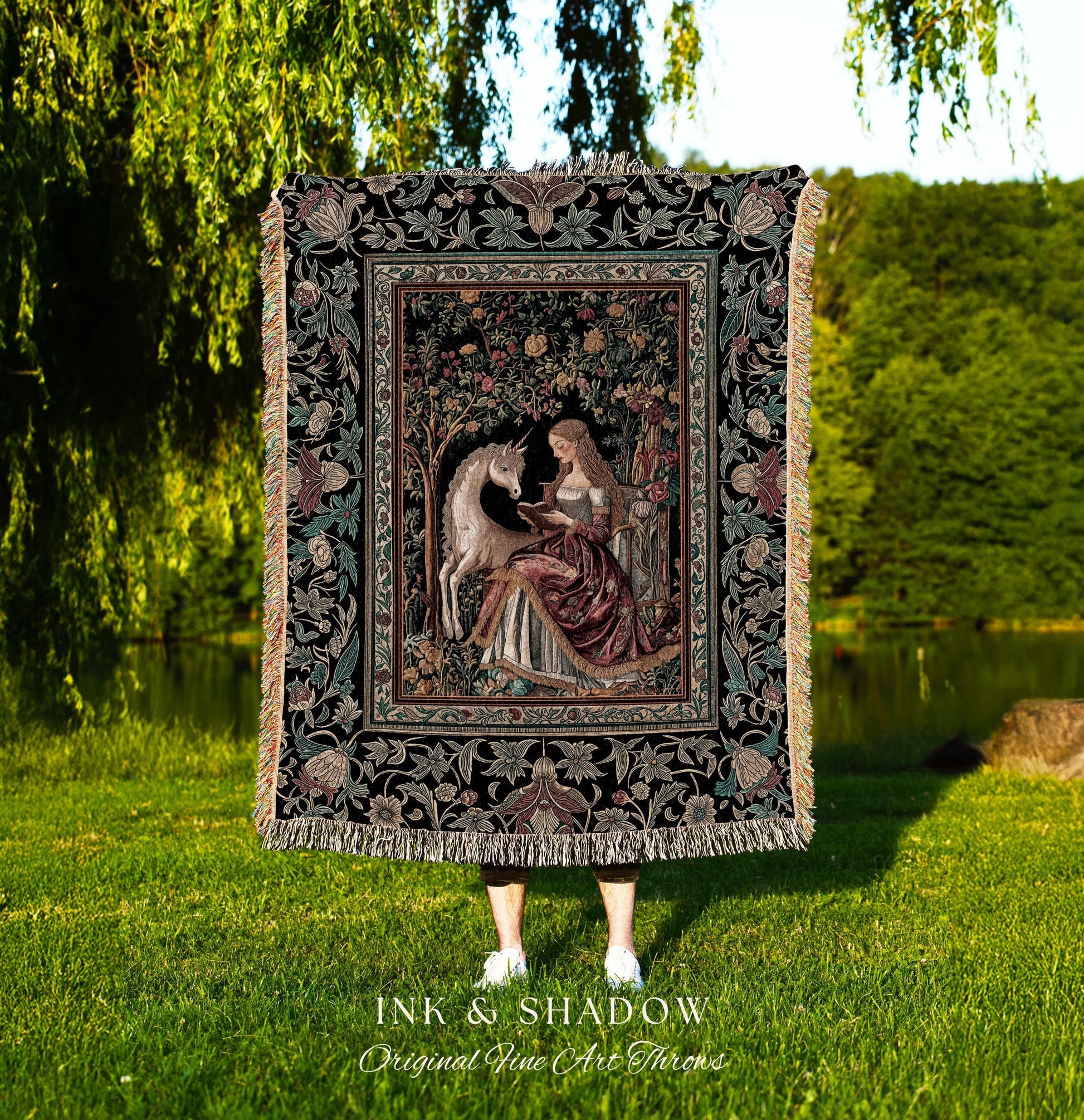 May include: A tapestry throw blanket featuring a medieval scene with a unicorn and a woman reading. The throw has a black background with floral and foliage patterns. The text "INK & SHADOW Original Fine Art Throws" is at the bottom.