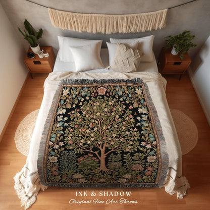 May include: A black throw blanket with a tree of life design, featuring green, pink, and blue floral accents. The blanket is fringed and rests on a bed with white bedding. The text "INK & SHADOW Original Fine Art Throws" is at the bottom.