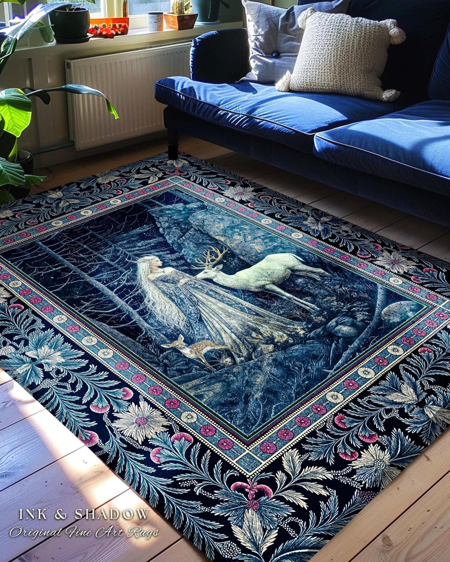 May include: A blue and white rug with a floral border and a scene of a woman and a deer in a forest. The rug is on a wooden floor in a living room with a blue sofa and plants.