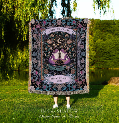 May include: A decorative throw blanket with a black background and a central design featuring two purple frogs, a crescent moon, and stars. The text "UNTIL WE CROAK" is at the top, and "DYLAN & GABBY 2025" is at the bottom. The blanket has a fringed edge.
