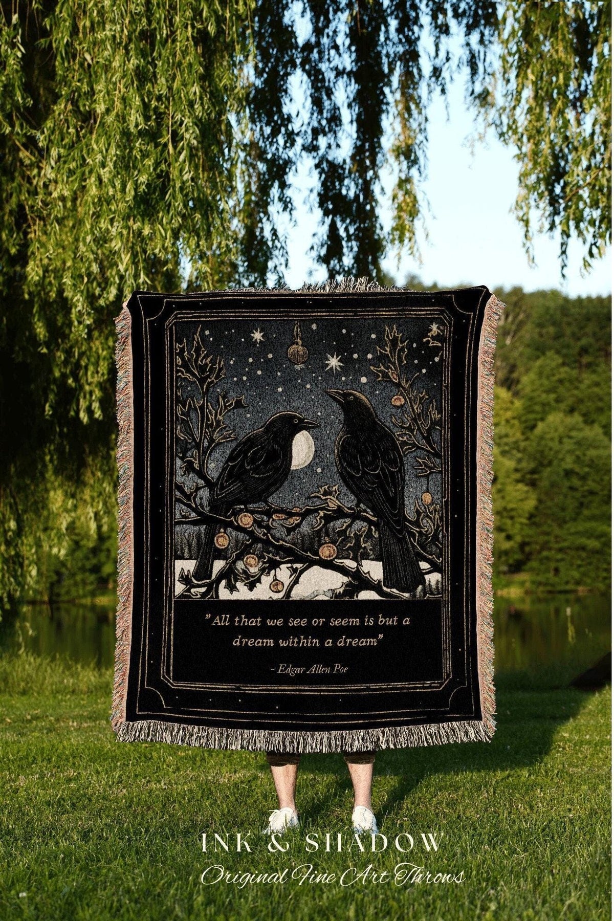 May include: Black throw blanket featuring two crows perched on a branch under a starry night sky with a full moon. The blanket has a quote from Edgar Allan Poe and the words "INK & SHADOW Original Fine Art Throws".
