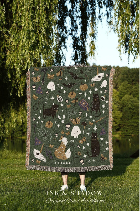 May include: Dark green throw blanket with a repeating pattern of black cats, skulls, bats, butterflies, and stars. The blanket has a fringed edge and the text "INK & SHADOW Original Fine Art Throws" at the bottom.
