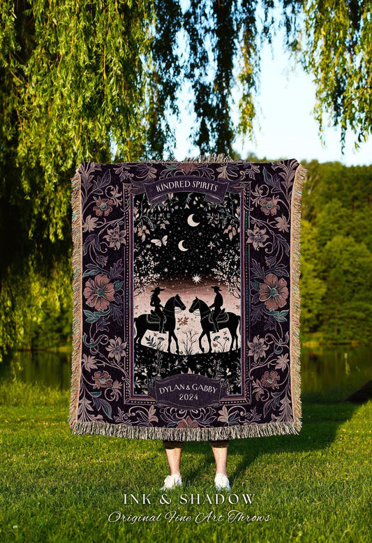 May include: A dark purple throw blanket with a romantic design featuring two riders on horseback under a starry night sky. The blanket has a floral border and the words "Kindred Spirits" and "Dylan & Gabby 2024".