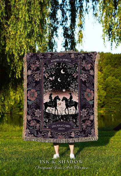 May include: A dark purple throw blanket with a romantic design featuring two riders on horseback under a starry night sky. The blanket has a floral border and the words "Kindred Spirits" and "Dylan & Gabby 2024".