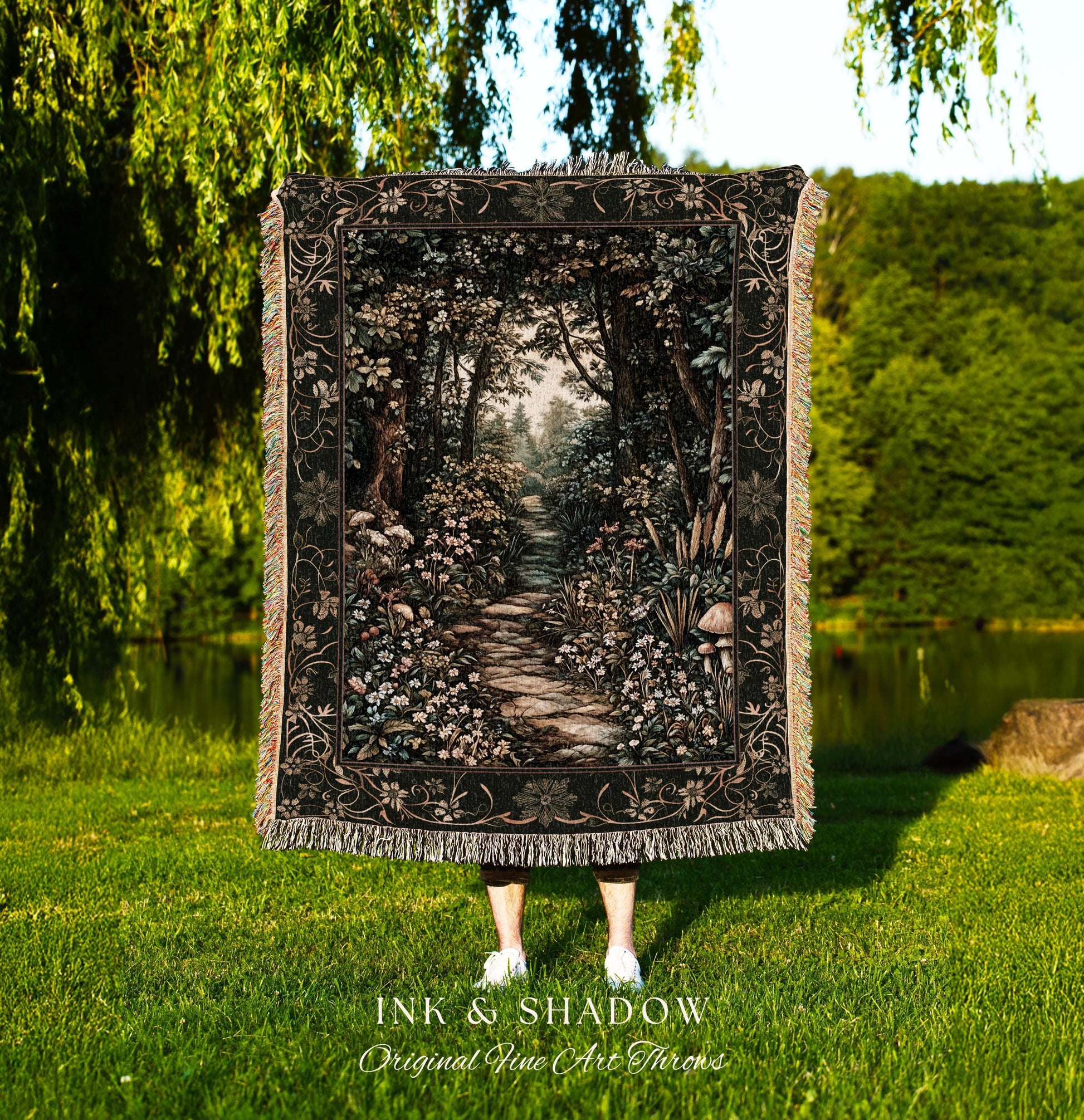 May include: A black throw blanket with a detailed forest scene, featuring a stone path winding through trees and flowers. The blanket has a decorative border and fringe. The text "INK & SHADOW Original Fine Art Throws" is at the bottom.