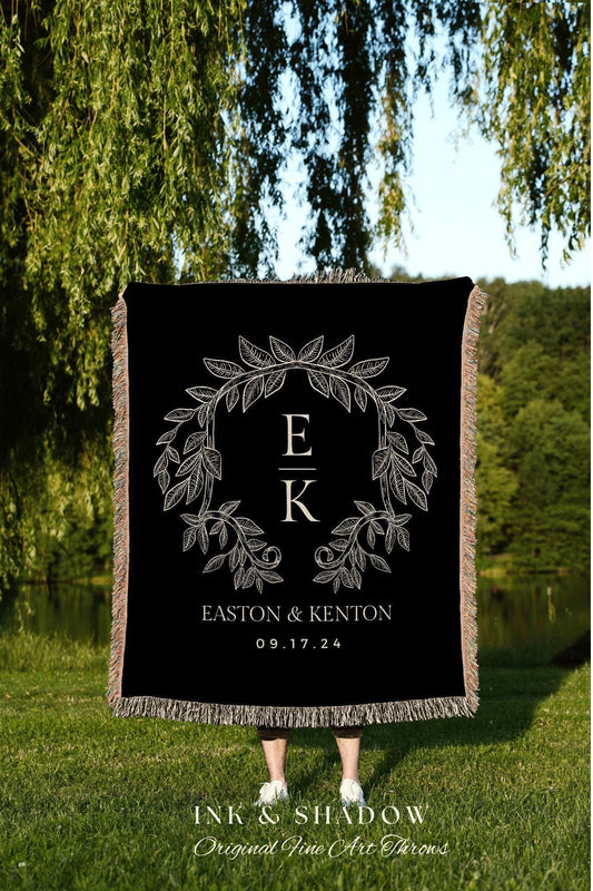 May include: Black throw blanket with a cream-colored floral wreath design, initials "E" and "K", and the names "Easton & Kenton" with the date "09.17.24". The blanket has fringed edges and the text "INK & SHADOW Original Fine Art Throws".
