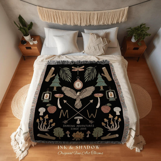 May include: Black throw blanket with a nature-themed design. Features an eagle, compass, trees, mushrooms, and the text "SHARING ADVENTURES SINCE 2015". The blanket has a fringed edge and the words "INK & SHADOW Original Fine Art Throws".