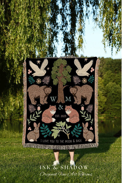 May include: Black throw blanket with a nature-themed design. Features owls, bears, foxes, rabbits, and a tree. Includes the text "W & M EST. 2023" and "I LOVE YOU TO THE MOON & BACK". Decorative fringe along the bottom.