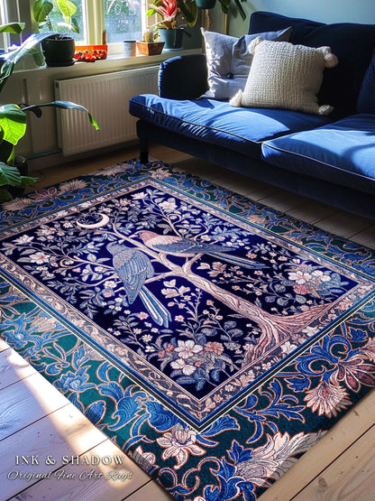 May include: A rectangular, dark blue rug with a detailed tree and bird design. The rug features a border with floral patterns in shades of blue, green, and pink. The text "INK & SHADOW Original Fine Art Rugs" is visible.