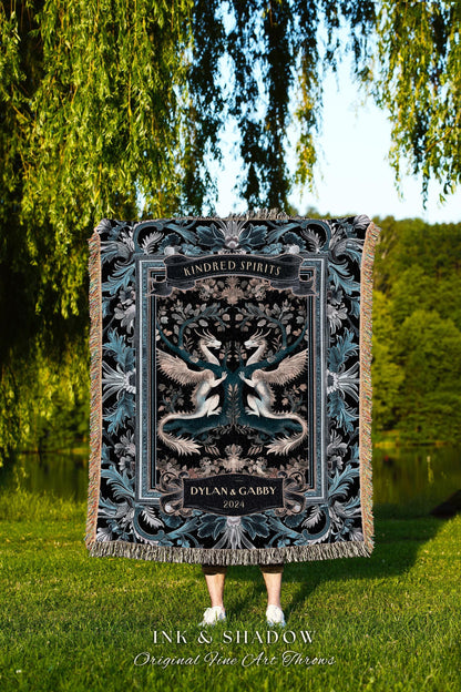 May include: A black and teal Kindred Spirits throw blanket featuring a symmetrical design of two dragons with outstretched wings. The blanket has a decorative border and the names Dylan & Gabby, and the year 2024 are displayed.