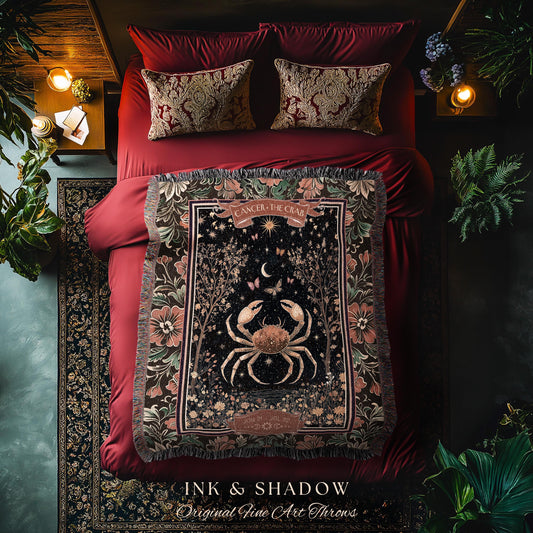 May include: A decorative throw blanket featuring a crab design, the Cancer zodiac sign. The blanket has a black background with floral and tree accents, and the text "CANCER - THE CRAB". The blanket is on a red bed with matching pillows.