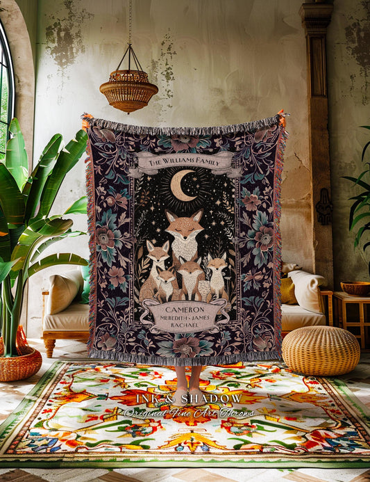 May include: A personalized woven throw blanket featuring a family of foxes under a crescent moon and stars. The dark background is adorned with floral patterns and the text "THE WILLIAMS FAMILY". The names "CAMERON, MEREDITH, JAMES, RACHAEL" are also displayed.
