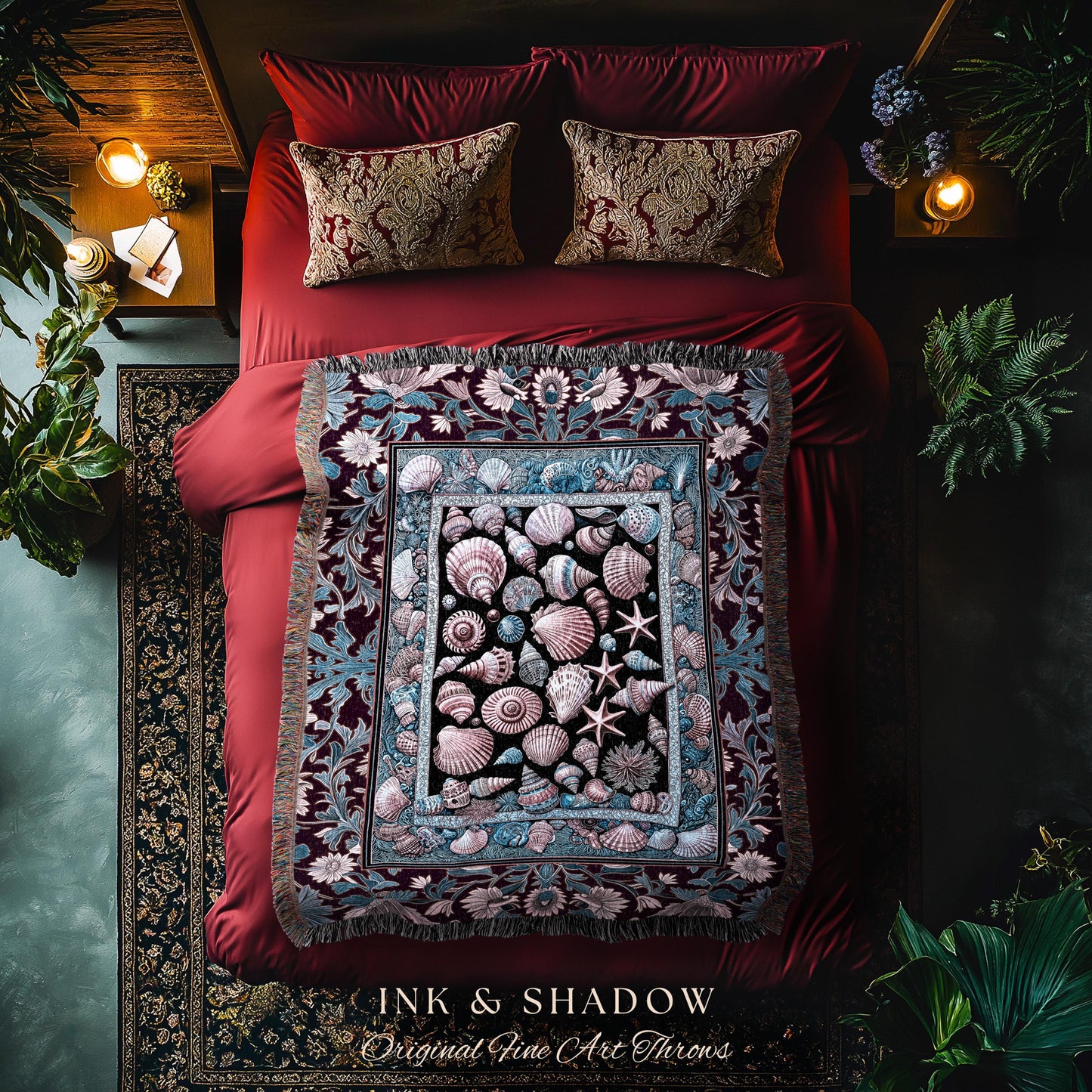 May include: A decorative throw blanket with a seashell design, featuring various shells and starfish in shades of pink, blue, and black. The blanket is displayed on a red bed with matching pillows. The text "INK & SHADOW Original Fine Art Throws" is visible.