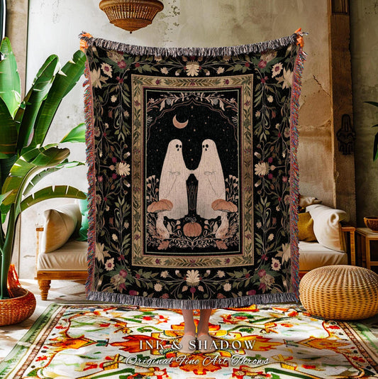 May include: A black throw blanket with a central design featuring two white ghost figures holding hands under a crescent moon and stars. The blanket has a floral border and fringe. The text "INK & SHADOW Original Fine Art Throws" is at the bottom.