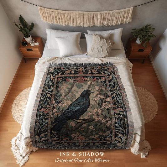 May include: A woven throw blanket featuring a detailed illustration of a black crow perched on a branch amidst flowering branches. The blanket has a dark border with floral patterns and fringe. The text "INK & SHADOW Original Fine Art Throws" is at the bottom.