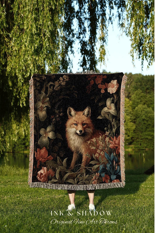 May include: A decorative throw blanket featuring a fox surrounded by flowers and foliage. The blanket has a dark background with a fringed edge. The text "INK & SHADOW Original Fine Art Throws" is at the bottom.