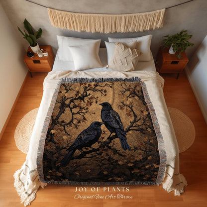 May include: A woven throw blanket featuring two black crows perched on a tree branch against a golden-brown background. The blanket has a fringed edge and the text "JOY OF PLANTS Original Fine Art Throws" at the bottom.