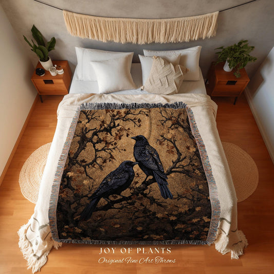 May include: A woven throw blanket featuring two black crows perched on a tree branch against a golden-brown background. The blanket has a fringed edge and the text "JOY OF PLANTS Original Fine Art Throws" at the bottom.