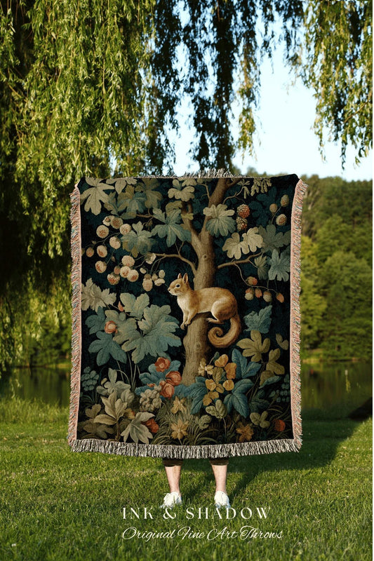 May include: A dark-colored throw blanket featuring a detailed illustration of a squirrel perched on a tree branch, surrounded by leaves and berries. The blanket has a fringed edge and the text "INK & SHADOW Original Fine Art Throws" at the bottom. The scene is set outdoors.