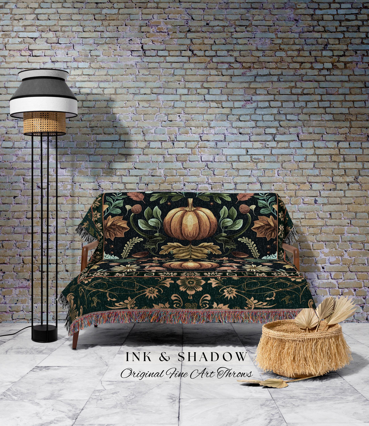 May include: A decorative throw blanket with a pumpkin design, draped over a wooden sofa. The blanket features a dark green background with a large pumpkin in the center, surrounded by leaves and floral patterns. The image also includes a floor lamp and a woven basket.