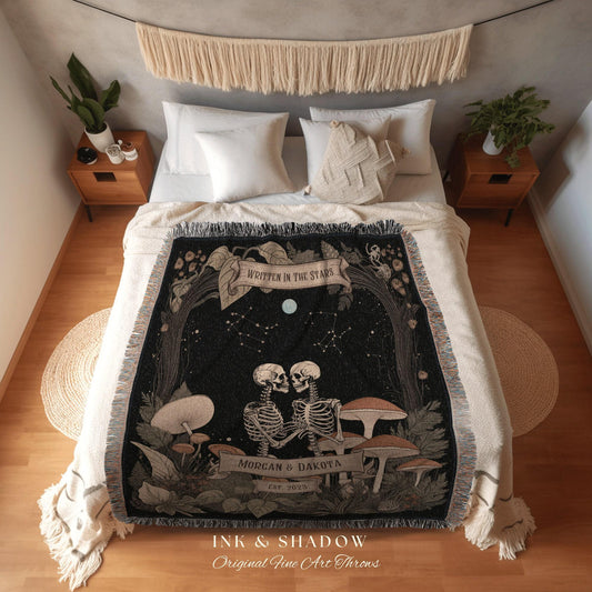 May include: A black throw blanket with a unique design featuring two skeletons embracing under a starry night sky. The words "WRITTEN IN THE STARS" are displayed on a banner. The blanket also includes the names "MORGAN & DAKOTA" and the year "EST. 2023".