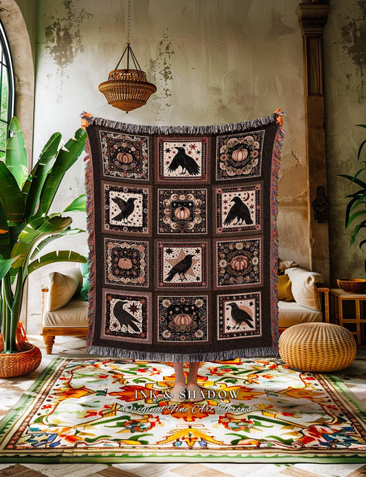 May include: A dark brown throw blanket with a repeating pattern of black crows, pumpkins, and stars in square panels. The blanket has a fringed edge and is displayed against a neutral background. The blanket is a decorative home textile.
