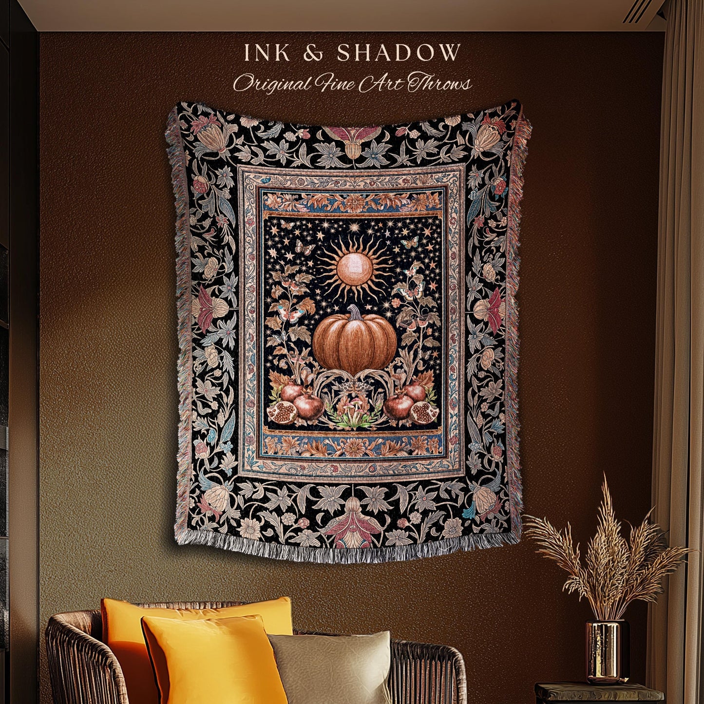 May include: A decorative throw blanket with a black background and a central design featuring a pumpkin, sun, and floral elements. The blanket has a fringed edge and the text "INK & SHADOW Original Fine Art Throws".