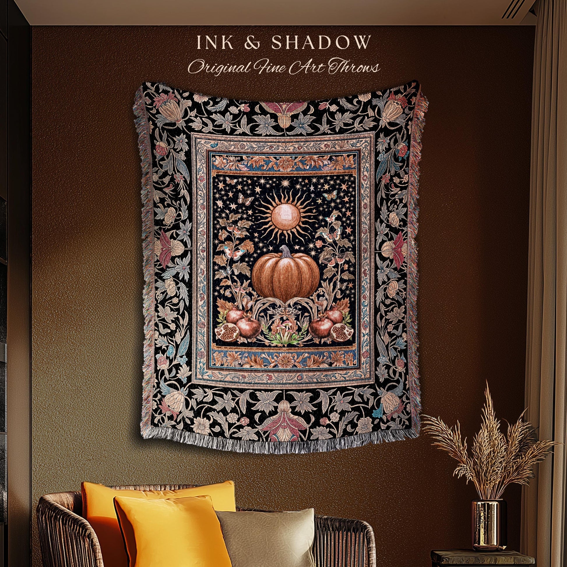 May include: A decorative throw blanket with a black background and a central design featuring a pumpkin, sun, and floral elements. The blanket has a fringed edge and the text "INK & SHADOW Original Fine Art Throws".