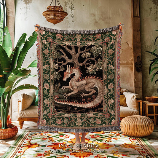 May include: A tapestry throw blanket with a detailed dragon design. The dragon is beige and red, set against a black background with a tree and floral elements. The border is green with floral patterns and fringed edges. The text "INK & SHADOW Original Fine Art Throws" is at the bottom.