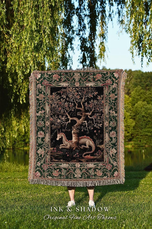 May include: A tapestry throw blanket with a detailed illustration of a tree, a unicorn, and a dragon. The blanket has a dark green border with floral patterns and fringe. The text "INK & SHADOW Original Fine Art Throws" is at the bottom.