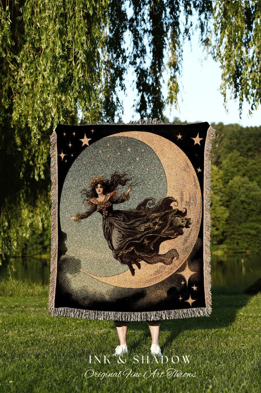 May include: A black throw blanket featuring a celestial design with a woman riding a crescent moon, surrounded by stars. The blanket has a fringed edge and the text "INK & SHADOW Original Fine Art Throws" at the bottom. The color palette includes black, gold, and gray.