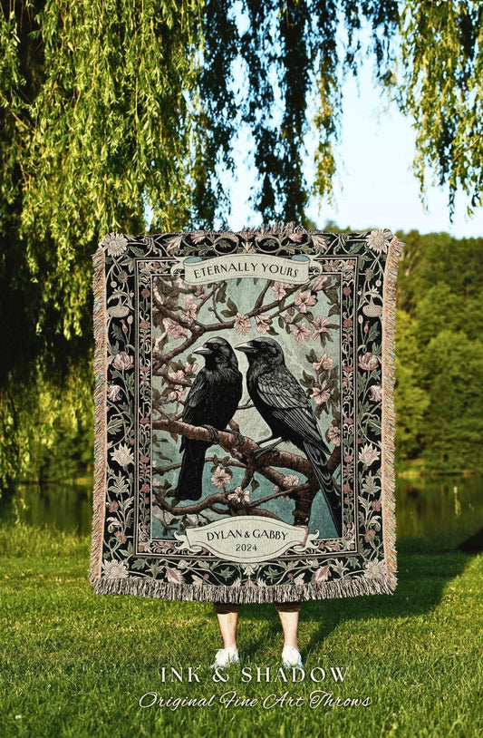 May include: A decorative throw blanket featuring two black crows perched on a flowering branch. The blanket has a black and floral border with the text "Eternally Yours" and "Dylan & Gabby 2024". The blanket is displayed outdoors on a sunny day.