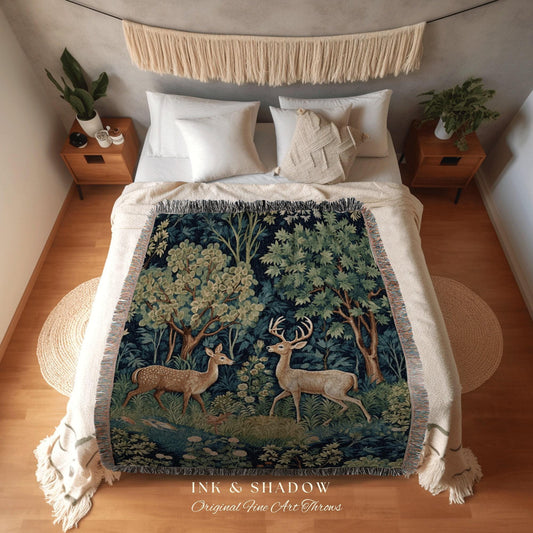 May include: A woven throw blanket featuring a forest scene with two deer. The blanket has a dark blue background with green and beige trees and foliage. The text "INK & SHADOW Original Fine Art Throws" is at the bottom.
