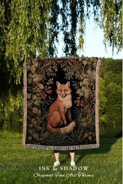 May include: A woven throw blanket featuring a detailed illustration of a fox in a forest setting. The blanket has a black background with brown, green, and beige accents. The text "INK & SHADOW Original Fine Art Throws" is at the bottom.