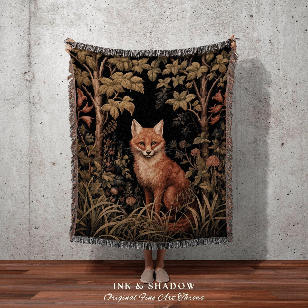 May include: A woven throw blanket featuring a detailed illustration of a fox in a forest setting. The artwork includes trees, foliage, and a black background. The blanket has a fringed edge and the text "INK & SHADOW Original Fine Art Throws".