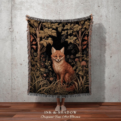 May include: A woven throw blanket featuring a detailed illustration of a fox in a forest setting. The artwork includes trees, foliage, and a black background. The blanket has a fringed edge and the text "INK & SHADOW Original Fine Art Throws".