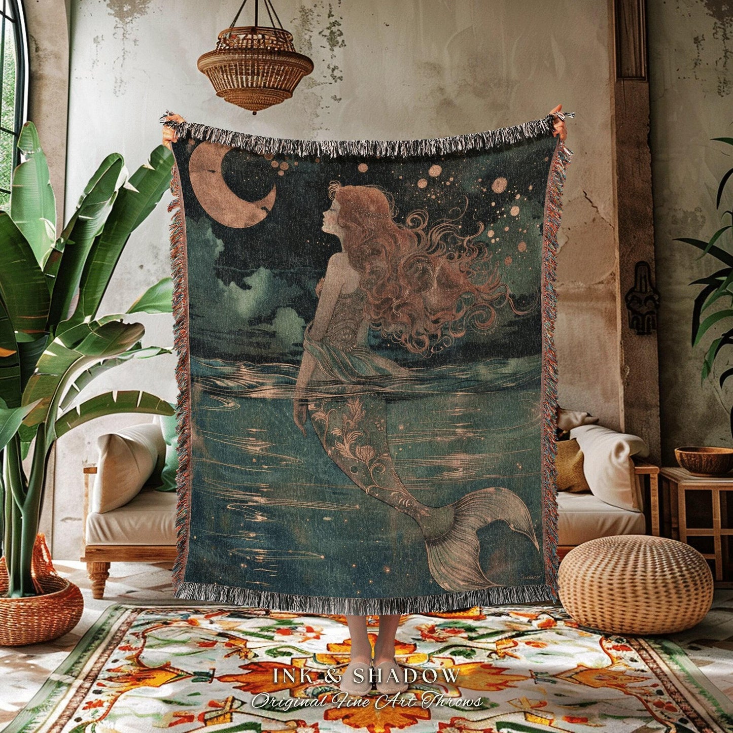 May include: A woven throw blanket featuring a mermaid illustration. The artwork depicts a mermaid with flowing red hair, a crescent moon, and a starry night sky. The blanket has a fringed edge and the text "INK & SHADOW Original Fine Art Throws".