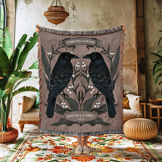 May include: A woven throw blanket featuring two black ravens facing each other, with the words "Forever & Always" above them. The blanket has a brown background with floral accents and the names "Dylan & Gabby" and the year "2024" below the ravens.