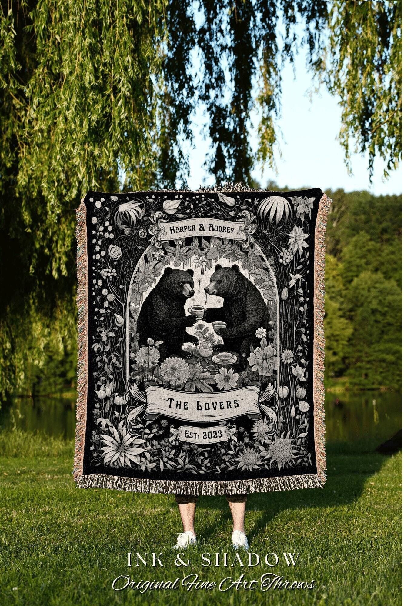 May include: Black and white throw blanket featuring two bears toasting with cups, surrounded by floral designs. The text "HARPER & AUDREY" and "THE LOVERS EST: 2023" are displayed on the blanket. The blanket has a fringed edge.