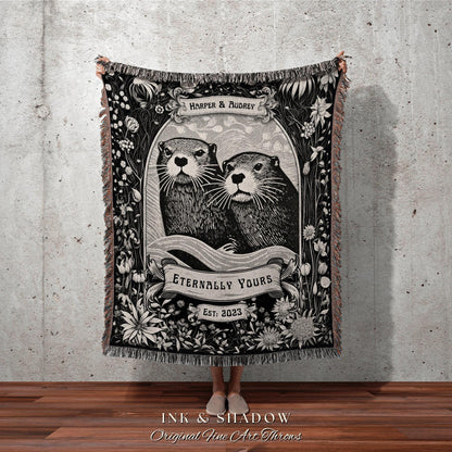 May include: Black and white throw blanket featuring an illustration of two otters within a floral frame. The blanket includes the text "HARPER & AUDREY", "ETERNALLY YOURS", and "EST: 2023". The bottom of the blanket reads "INK & SHADOW Original Fine Art Throws".