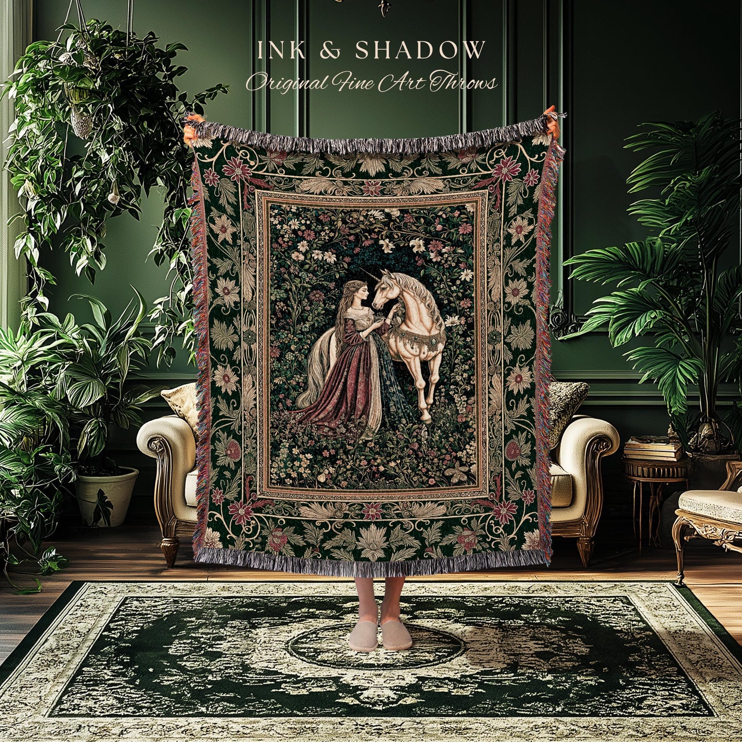 May include: A tapestry throw blanket featuring a medieval scene with a woman and a unicorn. The throw has a dark green background with floral and foliage patterns, and a fringed edge. The text "INK & SHADOW Original Fine Art Throws" is at the top.