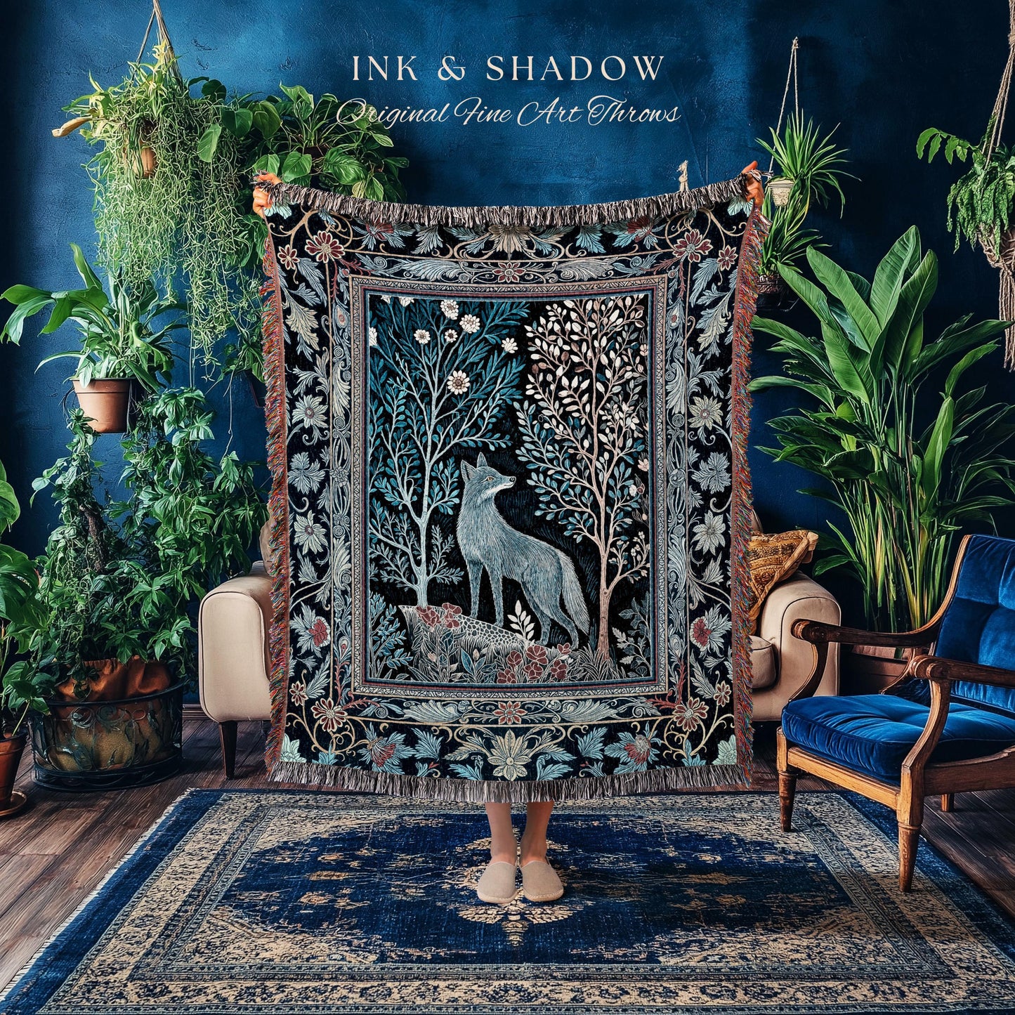 May include: A decorative throw blanket with a detailed forest scene featuring a wolf, trees, and floral elements in shades of blue, green, and white. The blanket has a black background and a fringed edge. The text "INK & SHADOW Original Fine Art Throws" is visible.